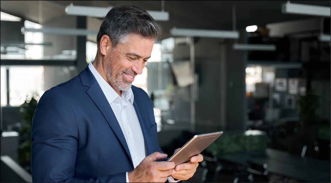 Business professional reviewing data on a tablet in a modern office.