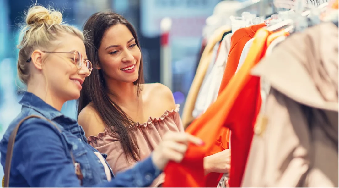 Two women shopping for clothes, discussing quality management principles