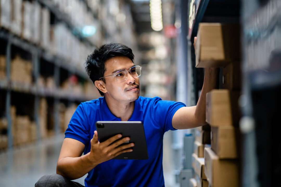 Warehouse worker with tablet inspects inventory, optimizing supply chain management.