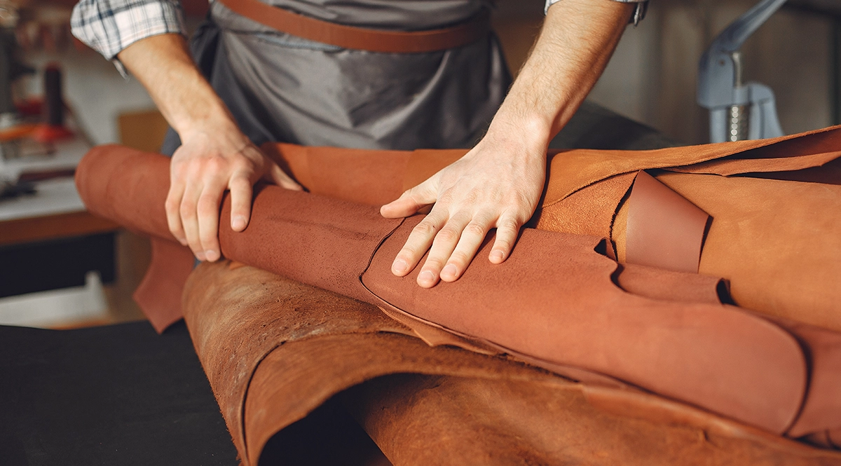 Leather craftsman rolling a hide, highlighting animal fibers in fashion.