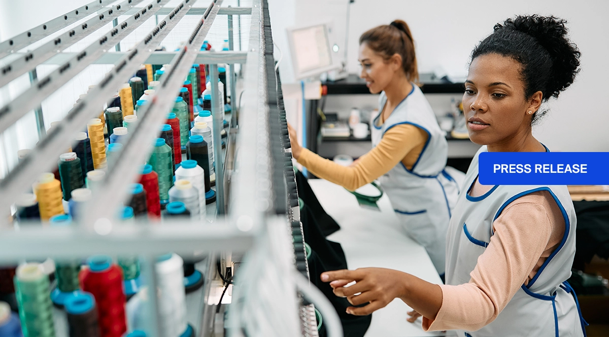 Workers inspect threads in a factory, symbolizing supply chain quality control.